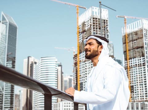 Man stood on a roof in front of skyscrapers looking up to the sky