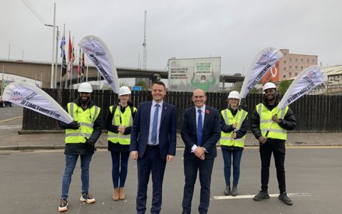 British Safety Council team in hi-vis with Time to Breathe flags beside an air pollution campaign billboard