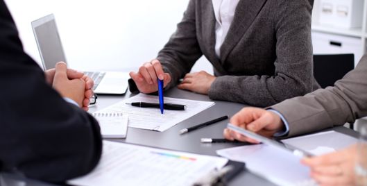 Three people sat at a table making notes on pieces of paper
