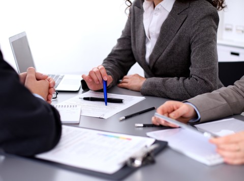 Three people sat at a table making notes on pieces of paper