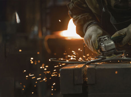 Worker using an angle grinder safely on metal in a workshop