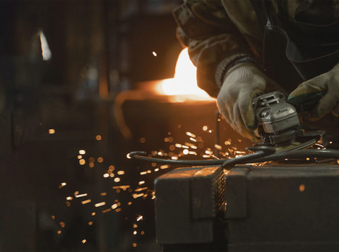 Worker using an angle grinder safely on metal in a workshop