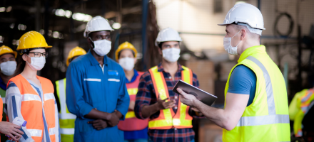 Employees being instructed by a health and safety officer while wearing PPE
