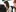 Red headed woman sat at a desk smiling with colleagues around her.