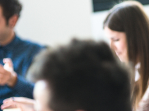Red headed woman sat at a desk smiling with colleagues around her