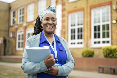 Black Teacher With File Outside School Istock 1364388460 Johnnygreig