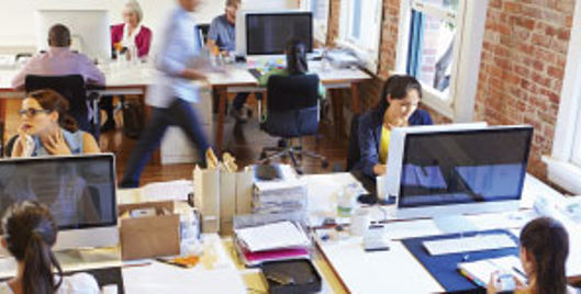 Group of people working at computers in a communal office