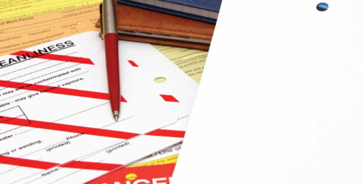 Workplace health and safety documents scattered on a table with a pen on top