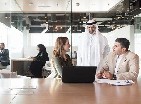 Three people having a discussion in a modern office.