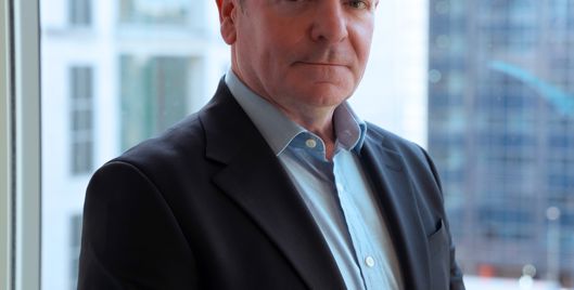 Rob Doyle, Group Health, Safety and Insurance Director at Amey, photographed against a city skyline backdrop