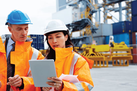 British Safety Council Consultancy Services - Man and woman on work site in hard hats and high visibility jackets looking at an i-pad