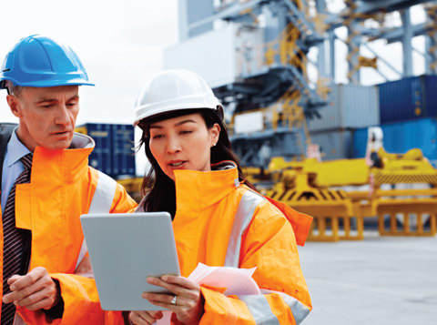 British Safety Council Consultancy Services - Man and woman on work site in hard hats and high visibility jackets looking at an i-pad