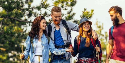 Two men and two women hiking in the woods having a conversation and looking happy