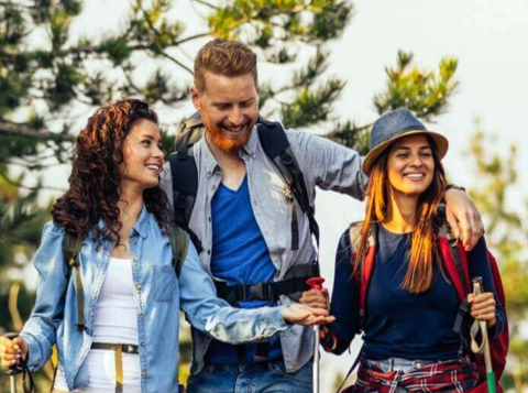 Two men and two women hiking in the woods having a conversation and looking happy