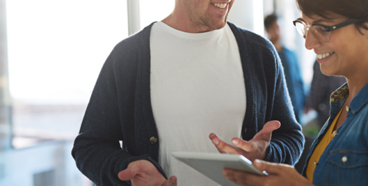 Man and woman stood in office having a conversation over a tablet