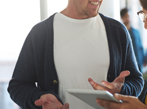 Man and woman stood in office having a conversation over a tablet