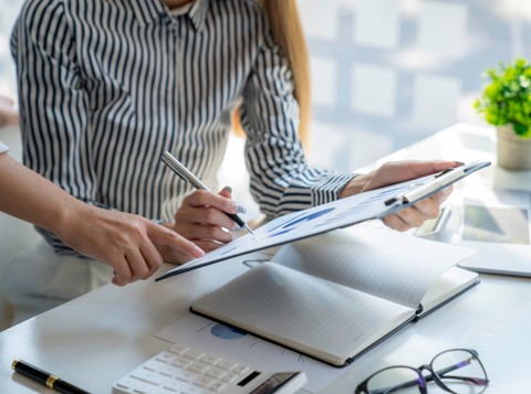 lady holding a document with a pen and graphs