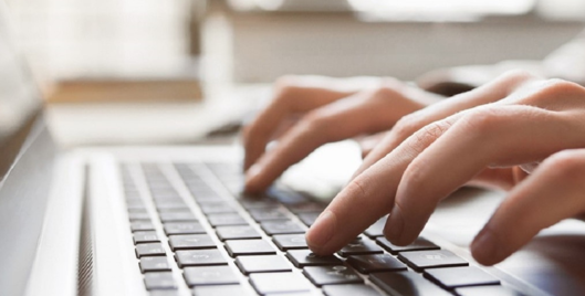 Person typing with both hands on laptop keyboard