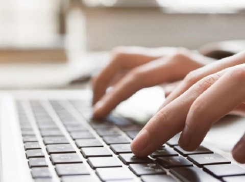 Person typing with both hands on laptop keyboard