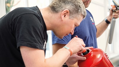Man shining torch into fire extinguisher while inspecting it