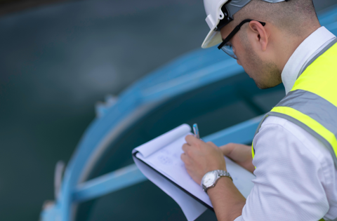 Worker in a hard hat reviewing a safety checklist on site