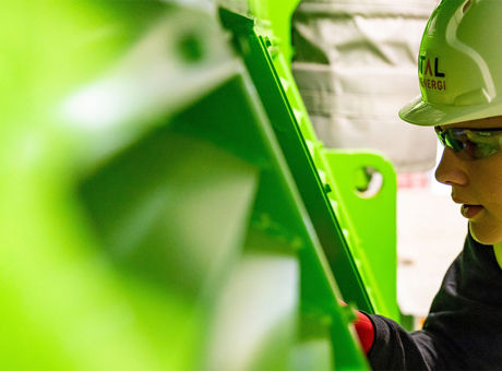 Factory worker beside industrial machinery with safety guarding in place.