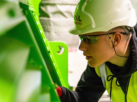 Factory worker beside industrial machinery with safety guarding in place.