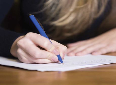 Person writing on a piece of paper at a desk