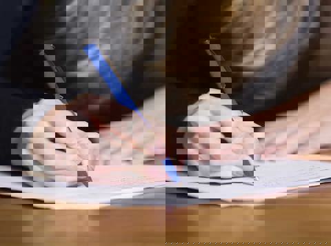 Person writing on a piece of paper at a desk