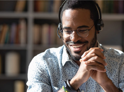 Man wearing headset smiling into distance with hands interlocked