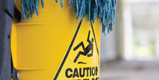 Blue mop in a yellow bucket labelled "Caution wet floor"