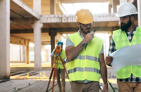 Two construction workers wearing PPE looking at plans on a construction site