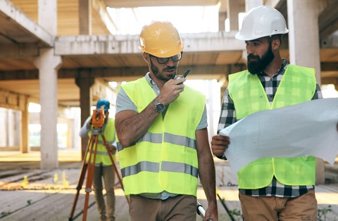 Two construction workers wearing PPE looking at plans on a construction site