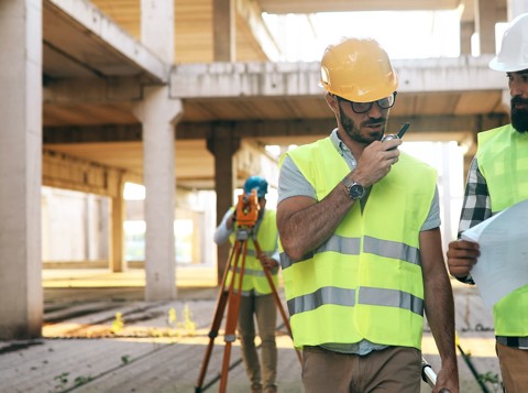 Two construction workers wearing PPE looking at plans on a construction site
