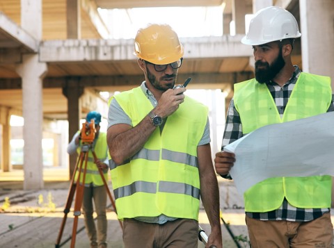 Two construction workers wearing PPE looking at plans on a construction site