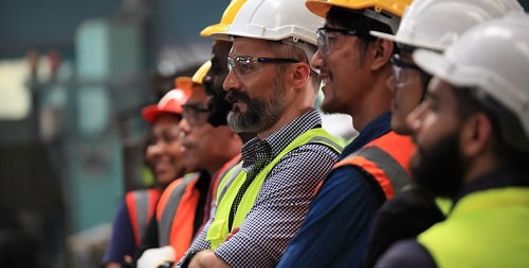 A row of men stood next to each other wearing high vis jackets and PPE