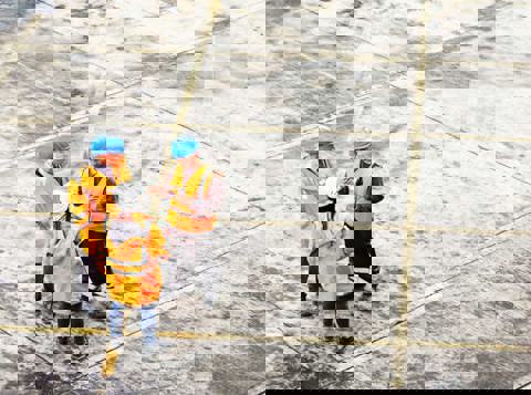 three people standing at the construction side wearing protective personal equipment