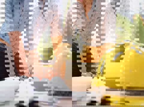Two people working on health and safety documents with a hard hat on the table next to them