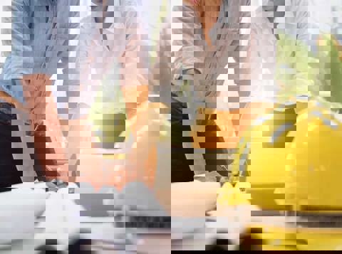 Two people working on health and safety documents with a hard hat on the table next to them