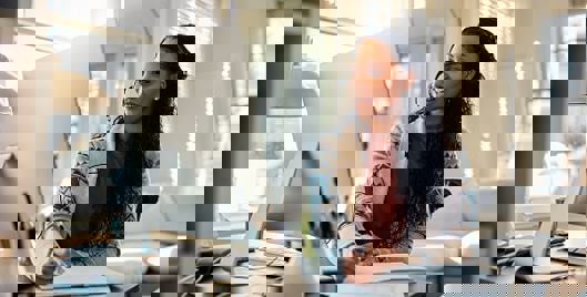 Woman sat at desk at home making notes and working at a computer