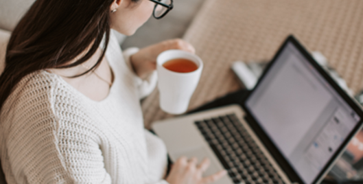 Woman working on laptop drinking a cup of tea