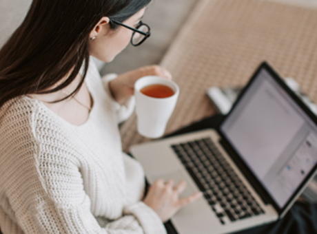 Woman working on laptop drinking a cup of tea