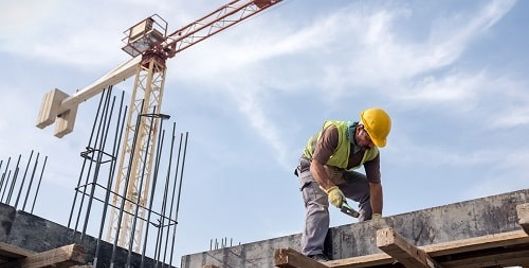 Man wearing PPE working on construction site with a crane in the background