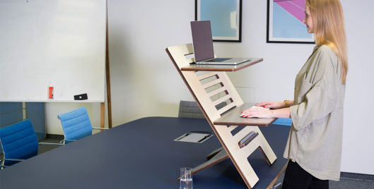 Woman using an adjustable standing desk as part of an ergonomic workplace setup