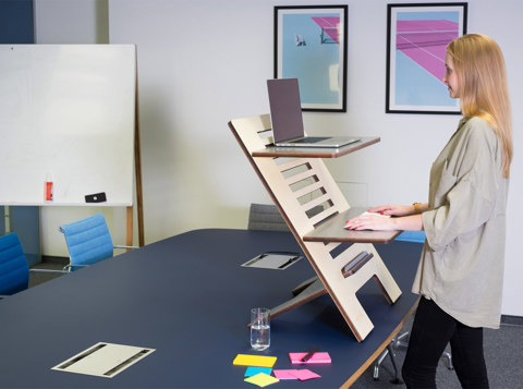 Woman using an adjustable standing desk as part of an ergonomic workplace setup