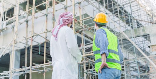 A man and a safety worker looking up at a construction site