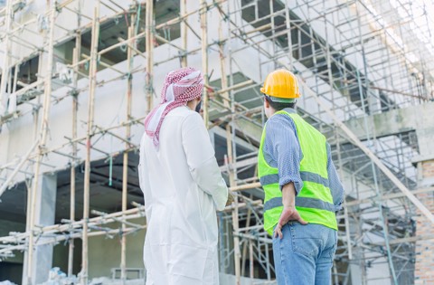 A man and a safety worker looking up at a construction site