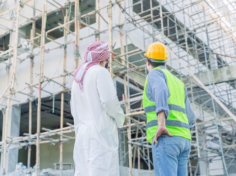 A man and a safety worker looking up at a construction site