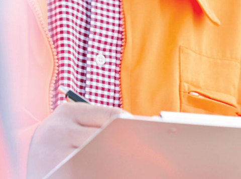 Man in orange hi vis writing on clipboard