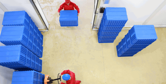 Overhead view of a warehouse with stacked blue containers used for manual handling risk assessment